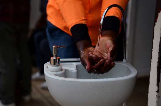 A man washes his hands at a public hand washing station before boarding a bus as a cautionary measure against the coronavirus at the Nyabugogo Bus Park in Kigali, Rwanda. March 11, 2020. REUTERS/Maggie Andresen