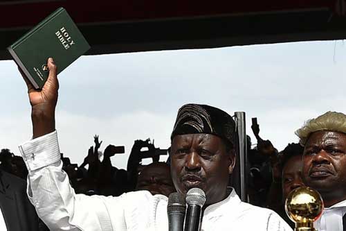 Kenya's opposition leader Raila Odinga (L) holds up a bible during his swearing in ceremony as the People's President of Kenya at Uhuru Park on January 30th, 2018.