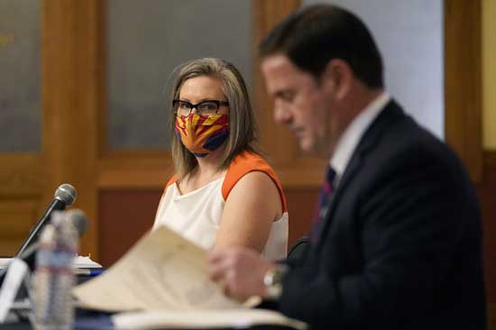 Arizona Secretary of State Katie Hobbs, left, watches as Arizona Gov. Doug Ducey signs election documents to certify the election results for federal, statewide, and legislative offices and statewide ballot measures at the official canvass at the Arizona Capitol Monday, Nov. 30, 2020, in Phoenix. (AP Photo/Ross D. Franklin, Pool)