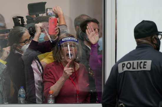 Election challengers yell as they look through the windows of the central counting board as police were helping to keep additional challengers from entering due to overcrowding, Wednesday, Nov. 4, 2020, in Detroit. (AP Photo/Carlos Osorio)
