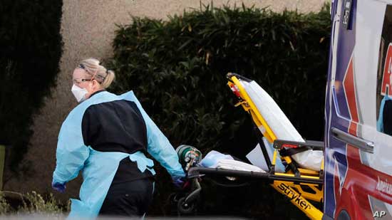 An ambulance worker wears protective equipment as she wheels a stretcher into a nursing facility where more than 50 people are sick and being tested for the COVID-19 virus, Feb. 29, 2020, in Kirkland, Wash.