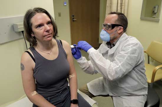 A pharmacist gives Jennifer Haller the first shot, March 16, 2020, in the first-stage safety study clinical trial of a potential vaccine for COVID-19, at the Kaiser Permanente Washington Health Research Institute in Seattle. 