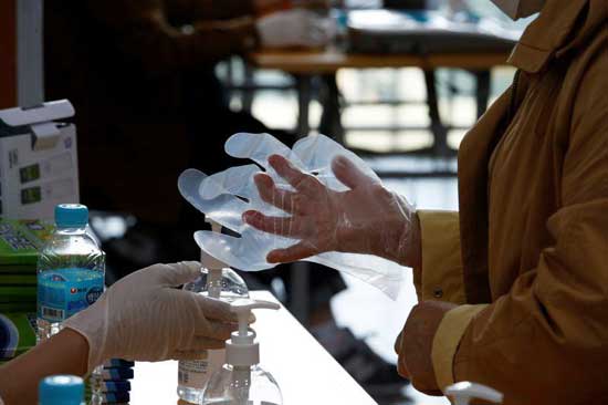 A woman dons plastic gloves to prevent contracting the coronavirus ahead of casting her ballot at a polling station in Seoul, South Korea, April 10, 2020. Reuters photo