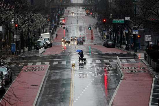 A lone person walks in the rain in a mostly deserted Times Square following the outbreak of Coronavirus disease (COVID-19), in the Manhattan borough of New York City, New York, U.S., March 23, 2020. REUTERS/Carlo Allegri