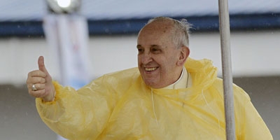  Pope Francis wearing a yellow poncho over his white robe to brave the heavy rain
