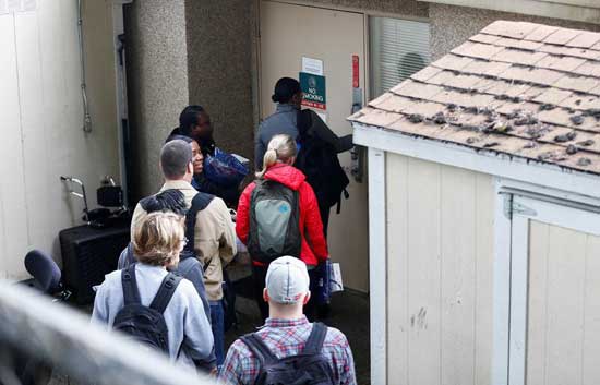 A group of people carrying medical scrubs arrive at the Life Care Center of Kirkland, a long-term care facility linked to several confirmed coronavirus cases, in Kirkland, Washington, U.S. March 8, 2020. REUTERS/Lindsey Wasson