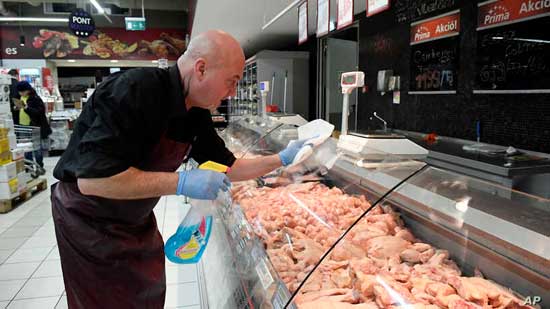  An employee disinfects the glass cover of a butcher counter to prevent the spread of the novel coronavirus in a food store in Budapest, Hungary, Wednesday, March 11, 2020.